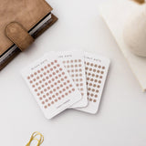 Planner along the edge of the image, with three sheets of sticker paper in transparent dots form in the colors blush, hazelnut, and nude, from Linespluspaper.